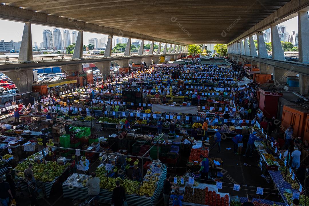 Pessoas no meio do galpão feira vendas frutas e verduras