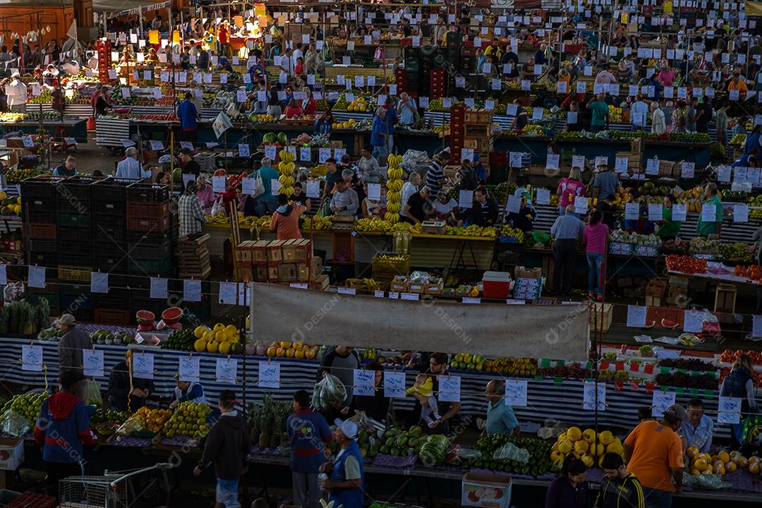 Pessoas no meio do galpão feira vendas frutas e verduras