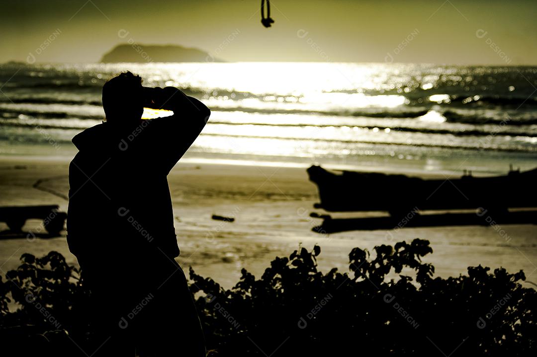 Homem na praia olhando paisagem por do sol mar