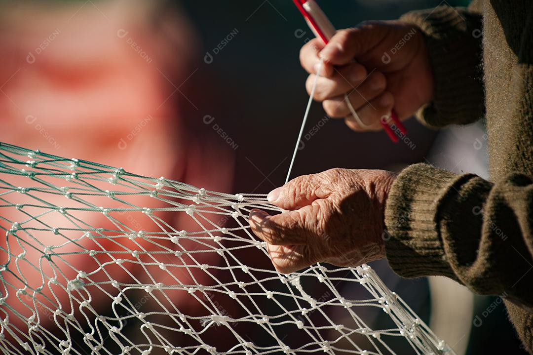 Mãos de pessoas costurando rede de pesca pescaria peixes