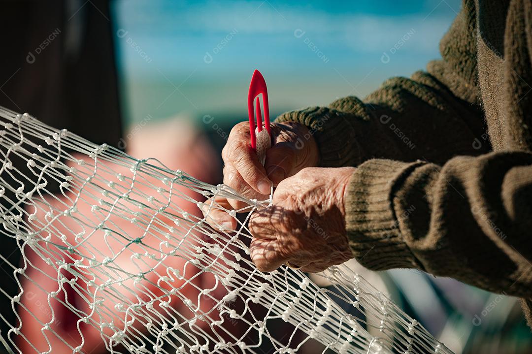 Mãos de pessoas costurando rede de pesca pescaria peixes