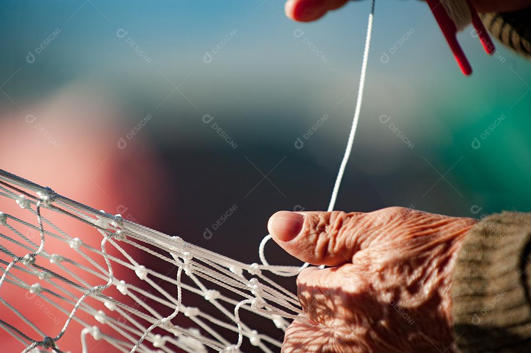 Mãos de pessoas costurando rede de pesca pescaria peixes
