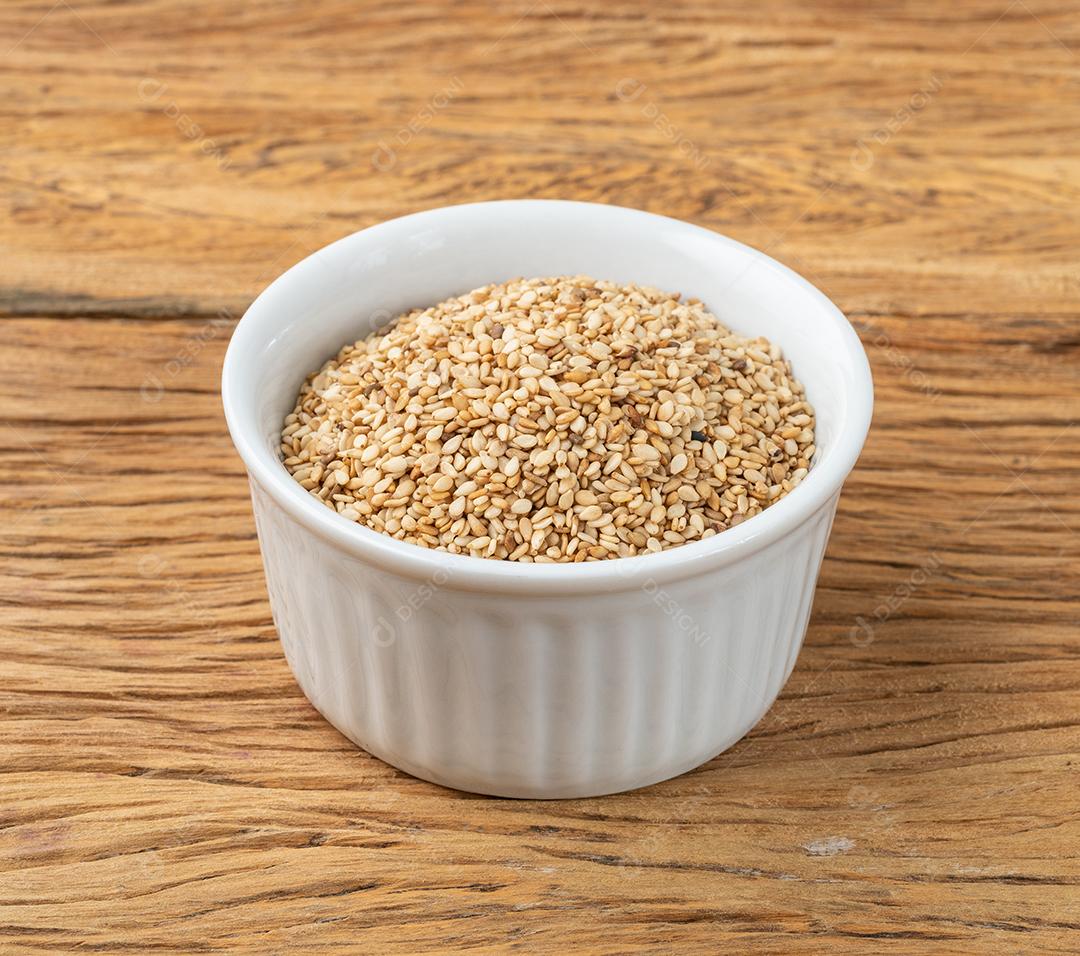 Sementes de gergelim em uma tigela sobre a mesa de madeira.
