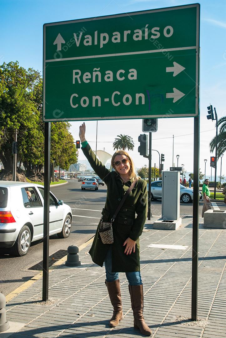 Mulher loira sendo fotografada perto de uma placa outdoor