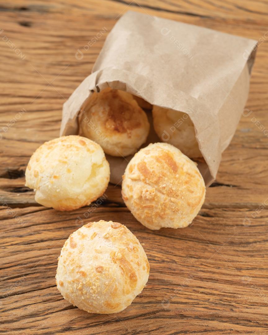 Pães de queijo brasileiro típicos em um saco de papel sobre a mesa de madeira