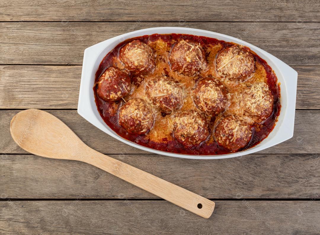 Bolas de carne em um prato branco com molho de tomate e queijo derretido