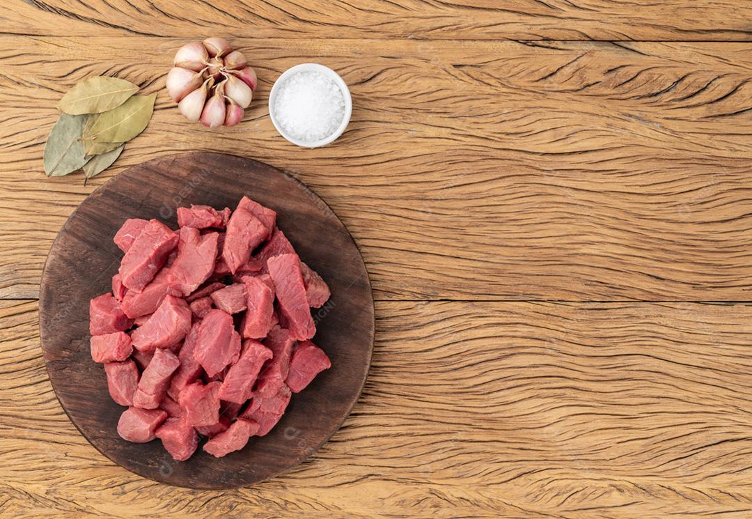 Carne picada na superfície sobre tábua de madeira com temperos e cópia