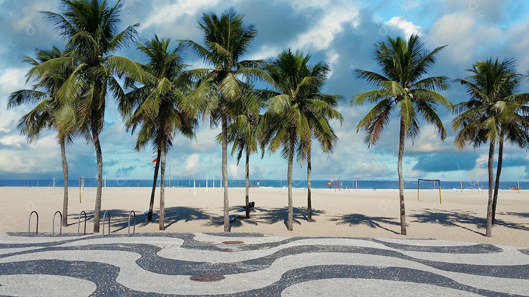 Calçadão da Praia de Copacabana Rio de Janeiro com palmeiras e céu azul.