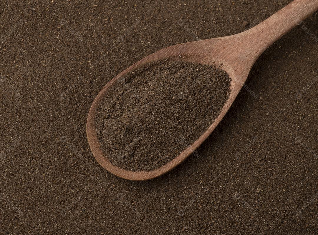 Vista superior, pimenta preta moída em uma colher de pau.