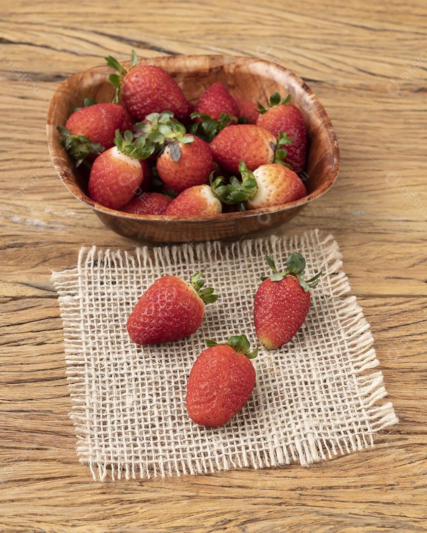 Morangos em uma tigela sobre mesa de madeira.