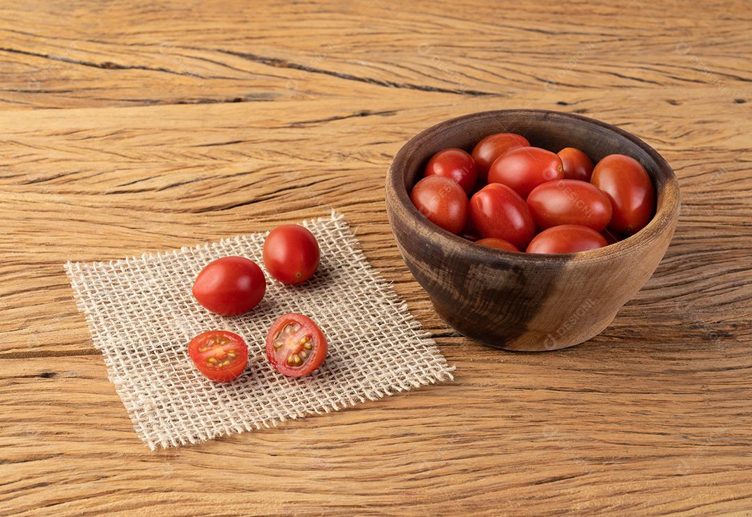 Tomates cereja em uma tigela sobre mesa de madeira.