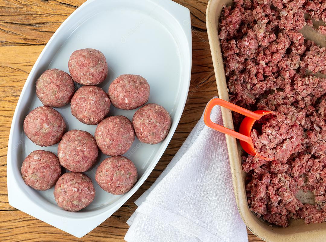 Bolas de carne crua sendo feitas com carne moída.