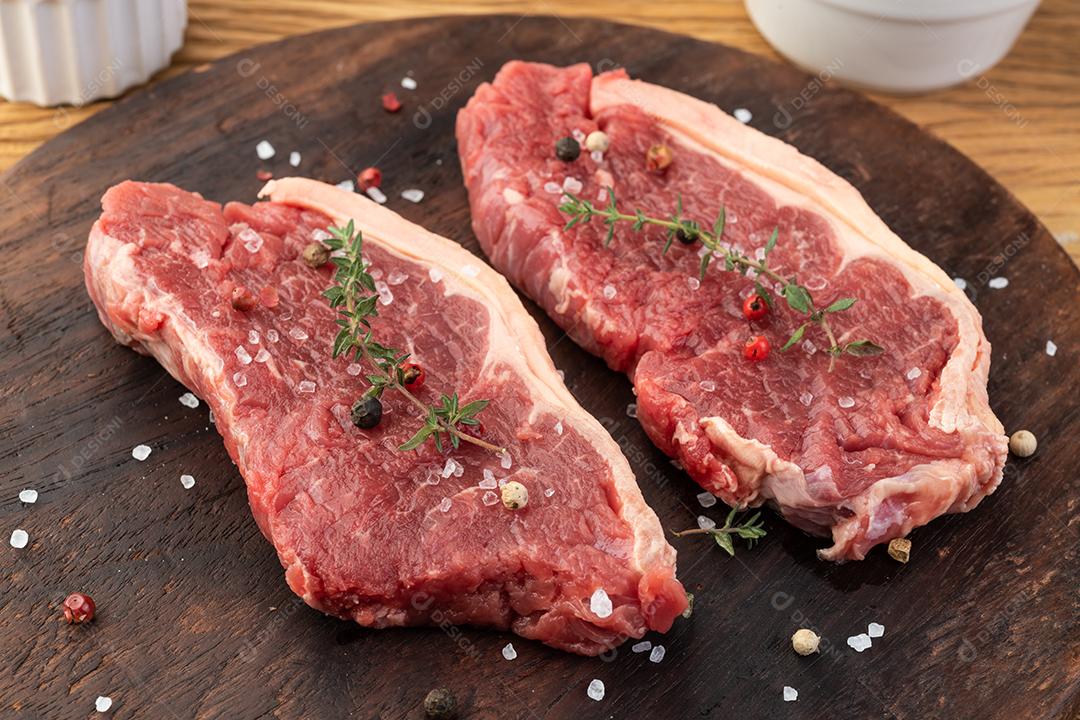 Carne de lombo de tira crua fatiada sobre tábua de madeira com temperos.