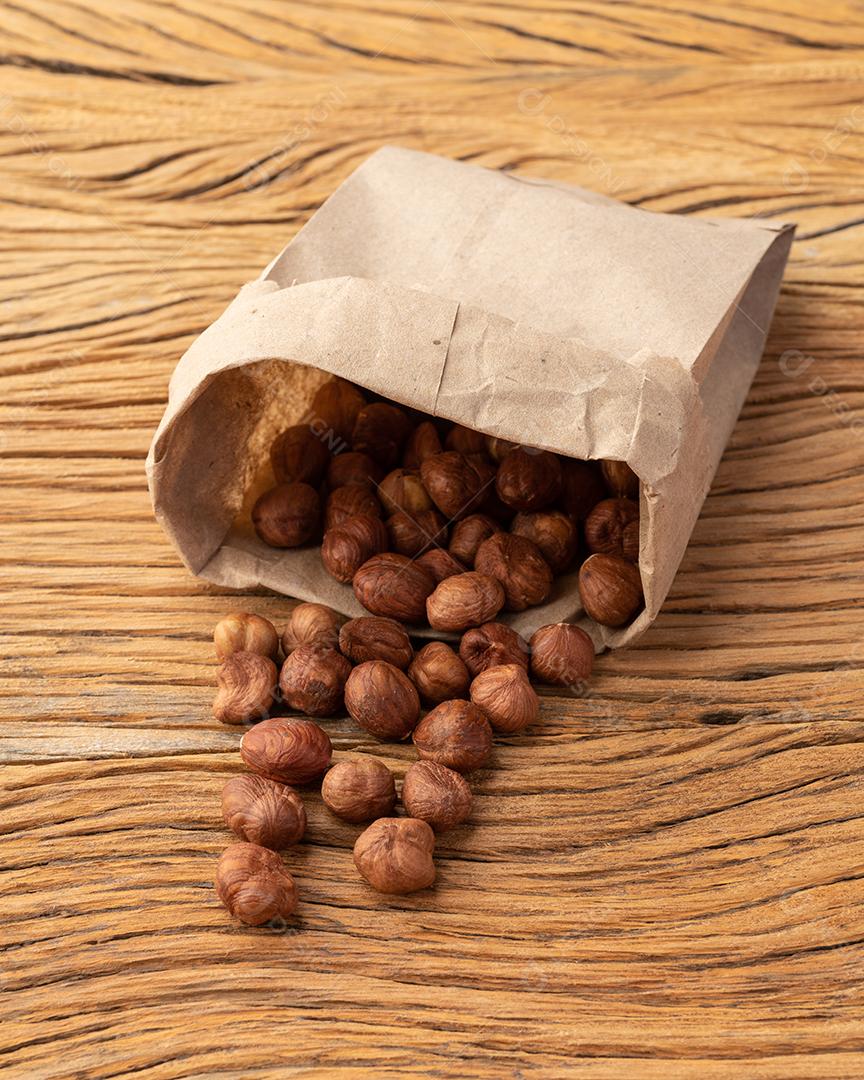 Avelãs em um saco de papel sobre a mesa de madeira.
