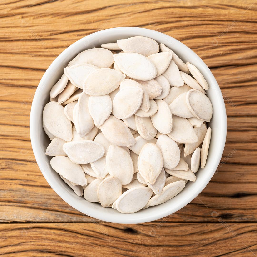 Sementes de abóbora em uma tigela sobre mesa de madeira.