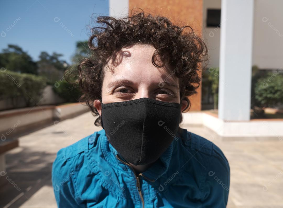 Mulher brasileira de cabelo encaracolado usando máscara em um dia ensolarado