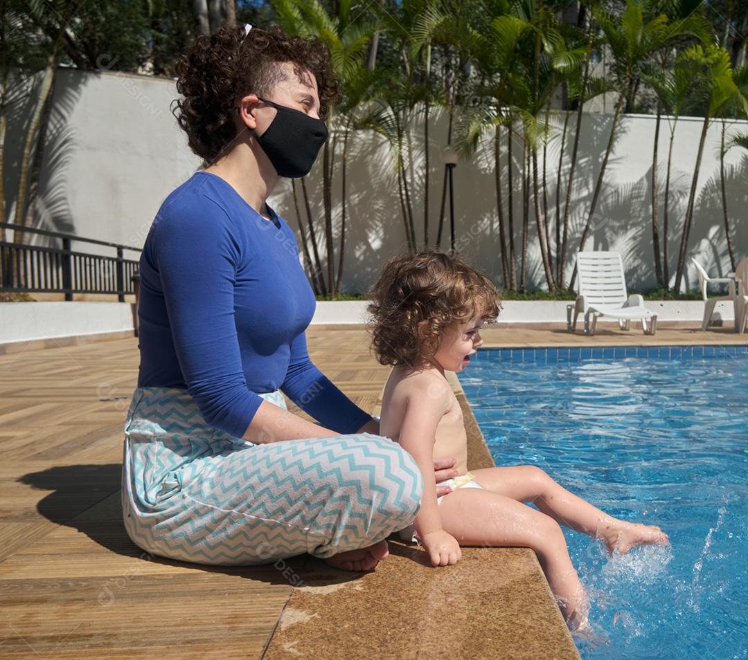 Mãe brasileira usando máscara e filha brincando na piscina em Sunny D