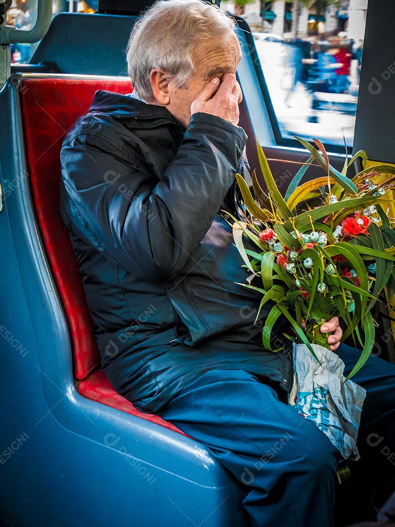 Velho sentado no ônibus carregando flores.Velho sentado no ônibus carregando flores.