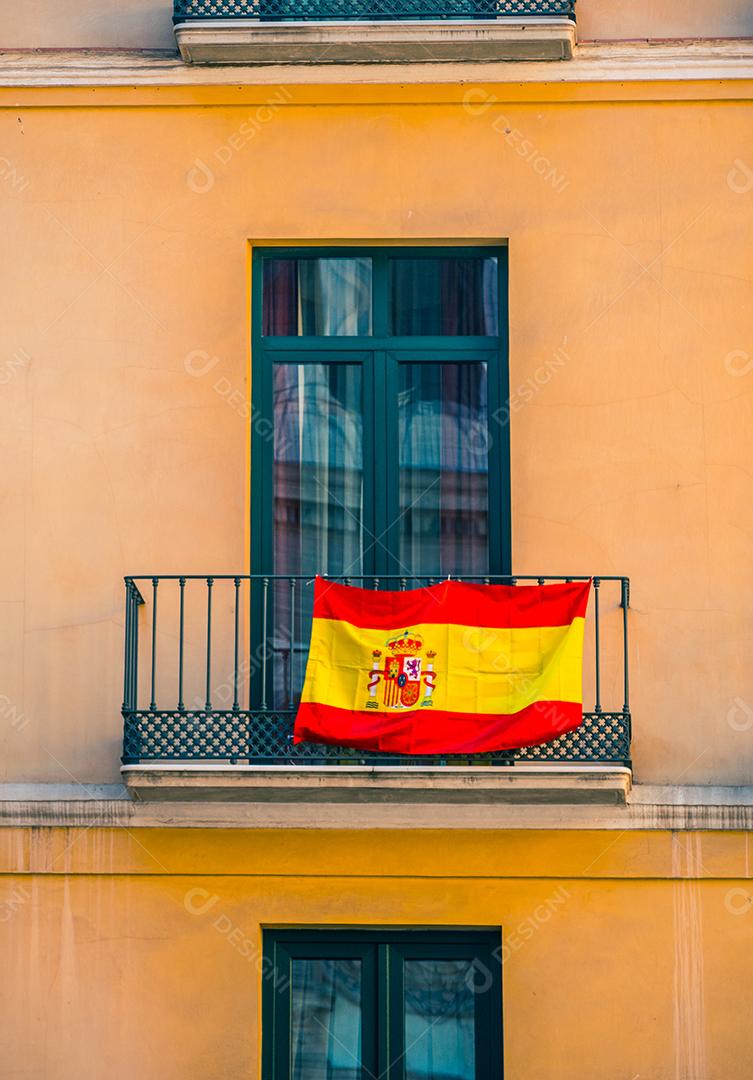 Feche a vista da fachada com janelas e bandeiras espanholas.