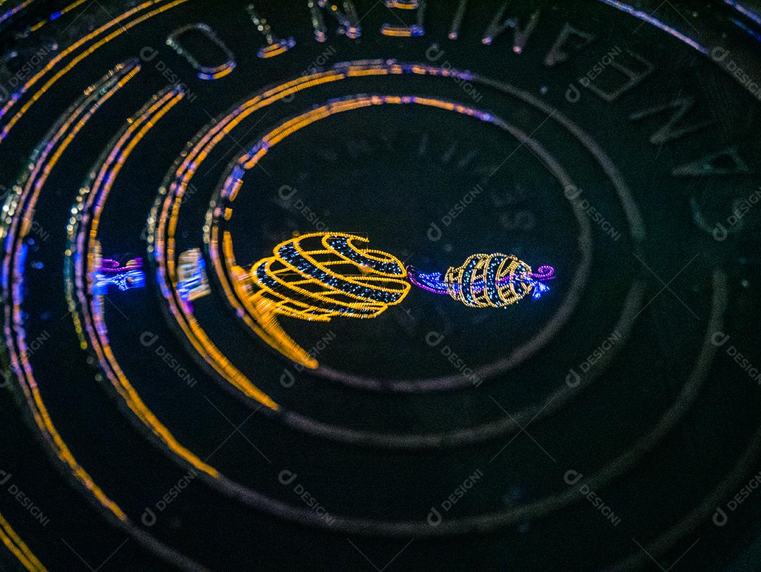 Reflexo de enfeites de Natal em bueiro molhado.