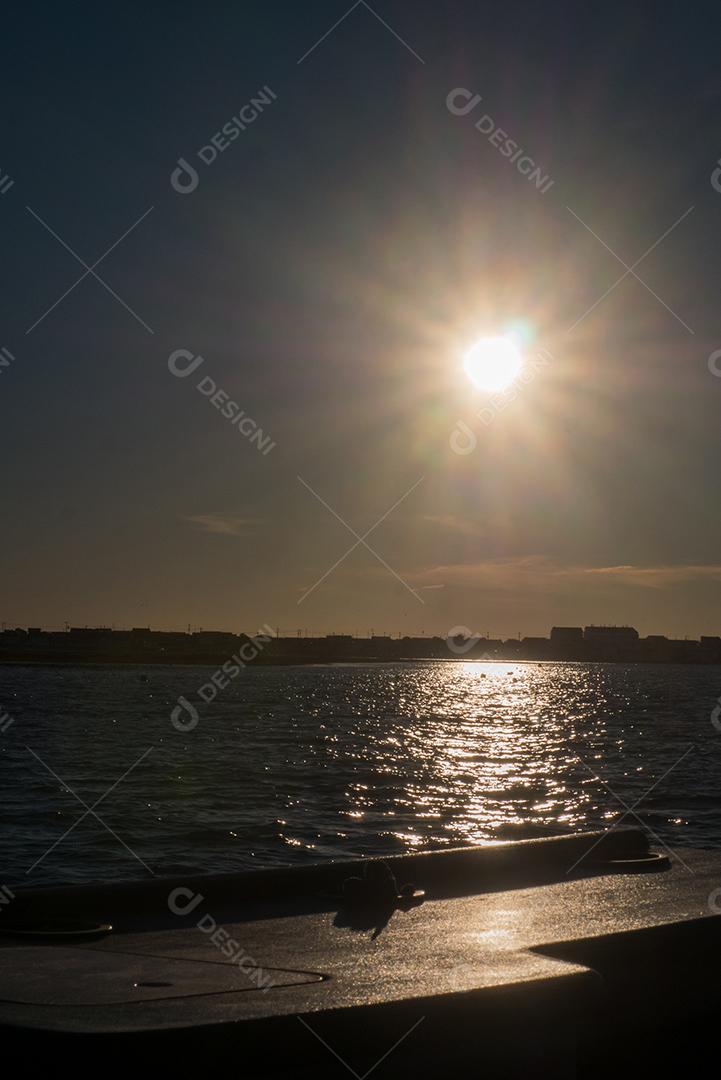 Sunset on the beach with sun in the sky.