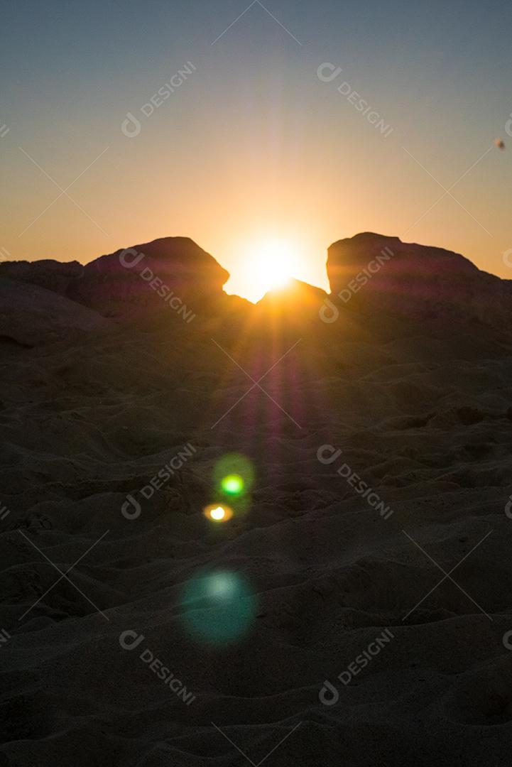 Pôr do sol na praia com sol no céu.