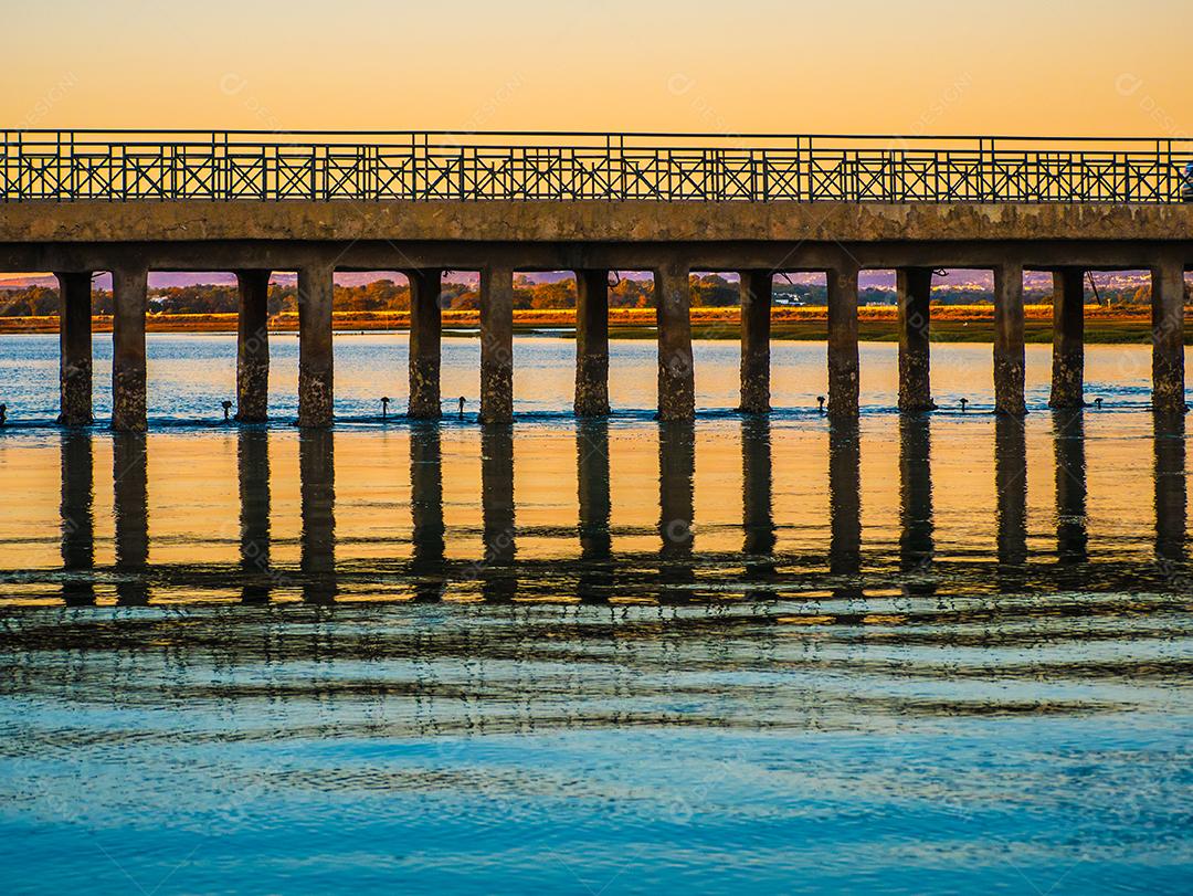 Pôr do sol na praia com sol no céu.