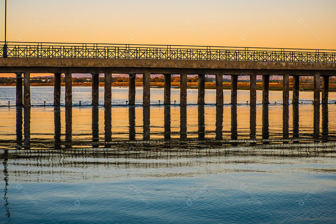 Pôr do sol na praia com sol no céu.
