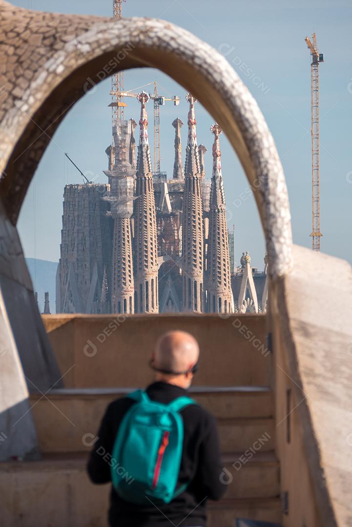 Homem olhando para a Catedral La Sagrada Familia através de um arco.