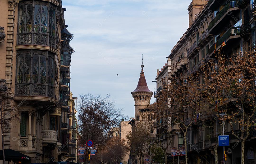 Edifícios nas ruas de Barcelona com uma torre ao fundo.