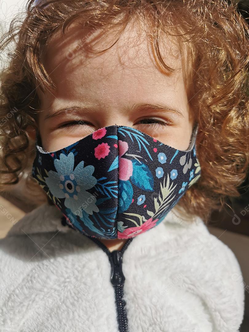 Brazilian girl smiling wearing mask outdoors.