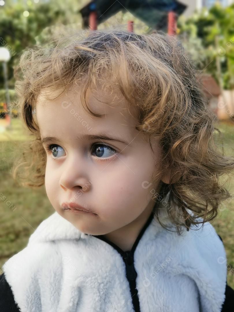 Menina brasileira olhando para o lado ao ar livre.