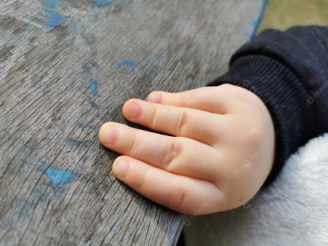 Mão do bebê segurando uma prancha de madeira vintage.