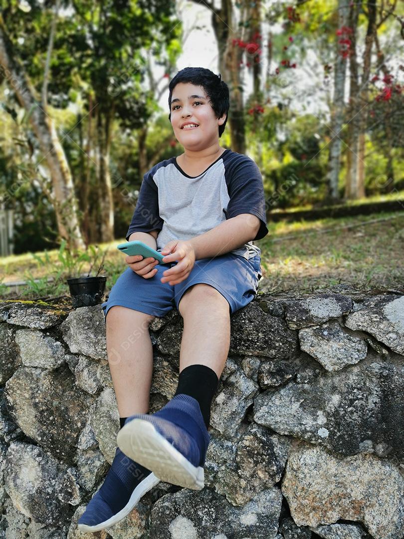 Sorriso de menino brasileiro segurando seu celular.
