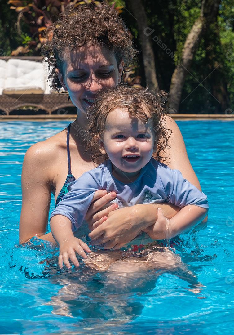 Vista de Mãe e Filha Brasileira brincando na piscina.
