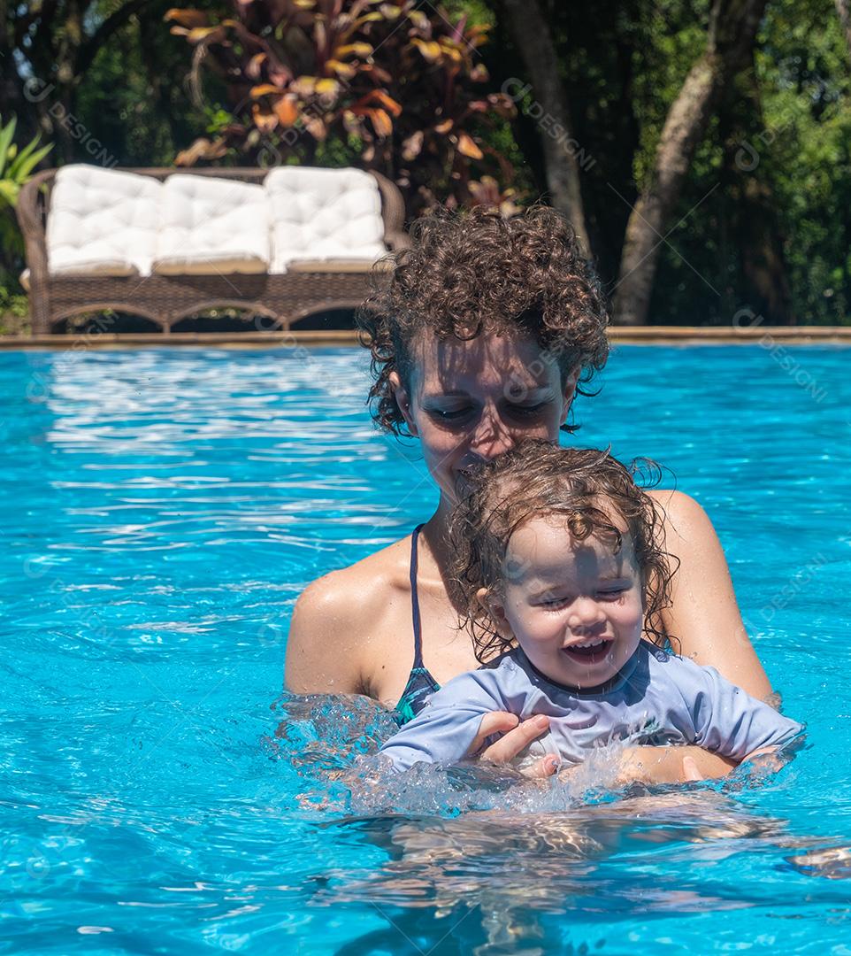 Vista de Mãe e Filha Brasileira brincando na piscina.