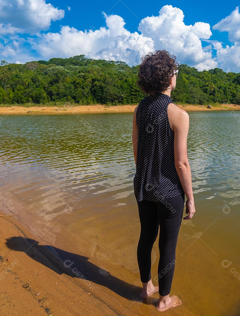 Vista de mulher relaxando olhando para o lago.