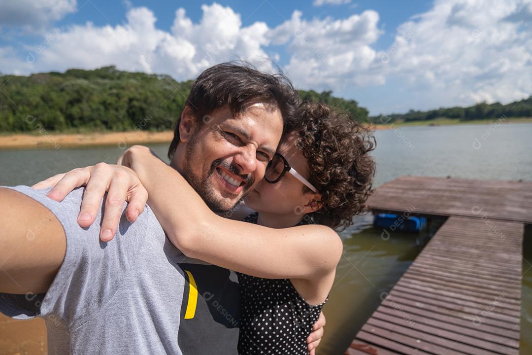 Selfie de um casal abraçando na natureza.