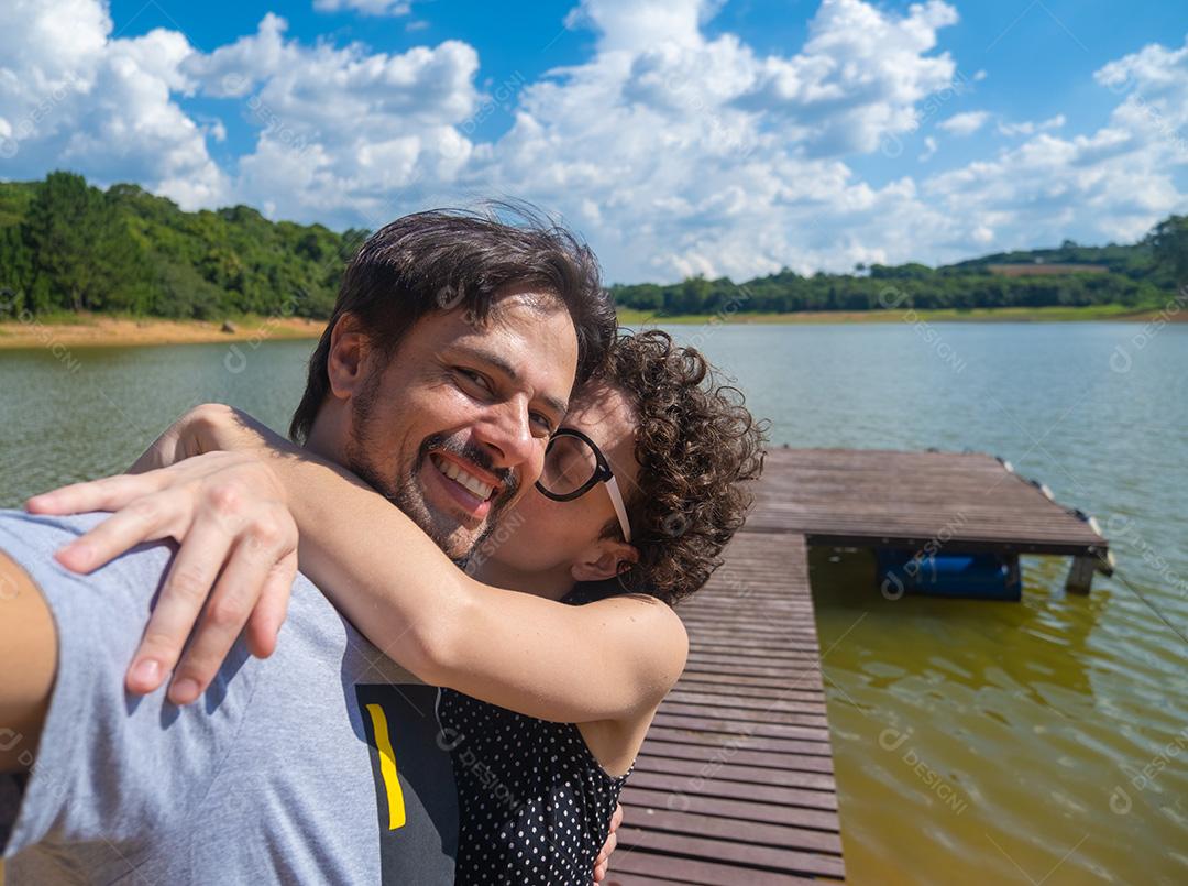 Selfie de um casal abraçando na natureza.