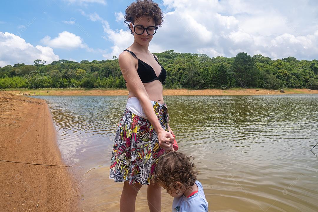 Mãe segurando a mão da filha na natureza.