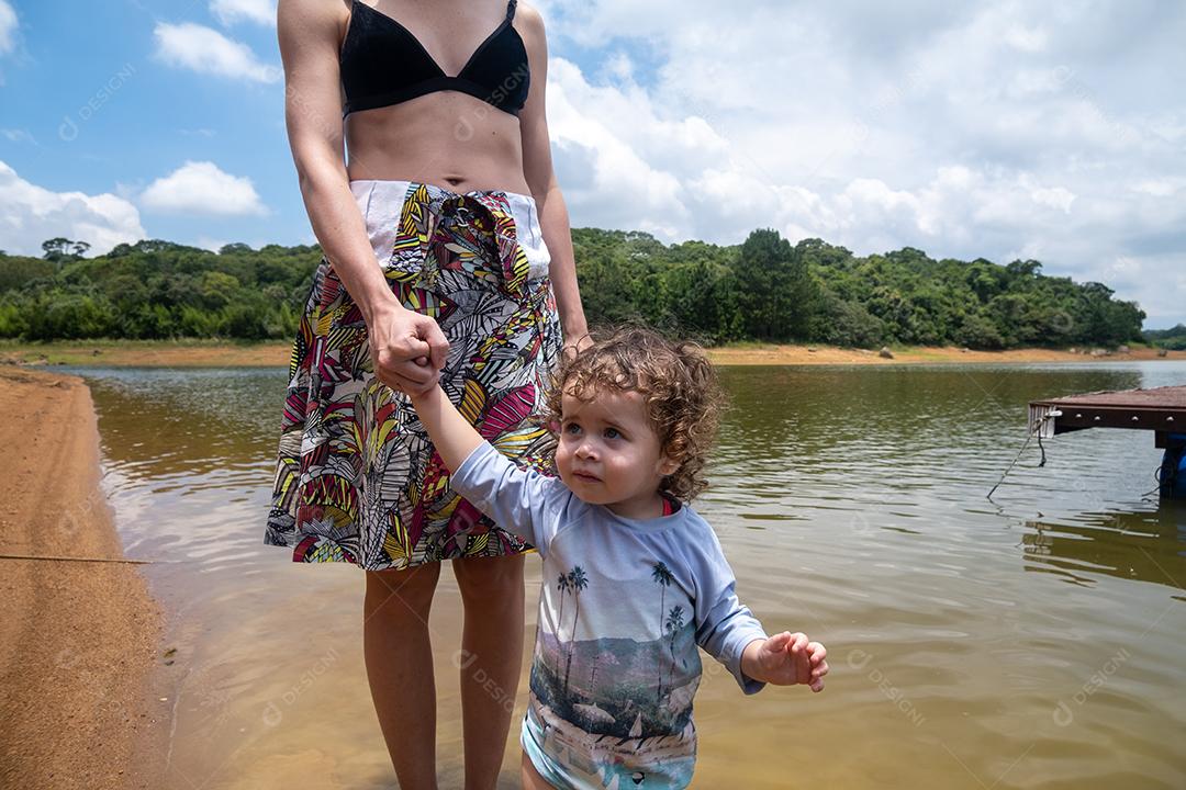 Mãe segurando a mão da filha na natureza.