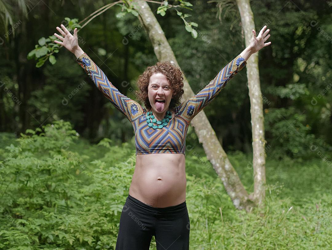 Jovem mulher moderna comemorando a gravidez na floresta.