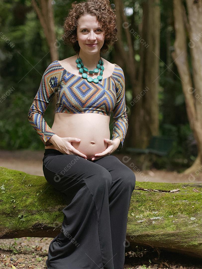 Mulher jovem moderna grávida tocando sua barriga ao ar livre.