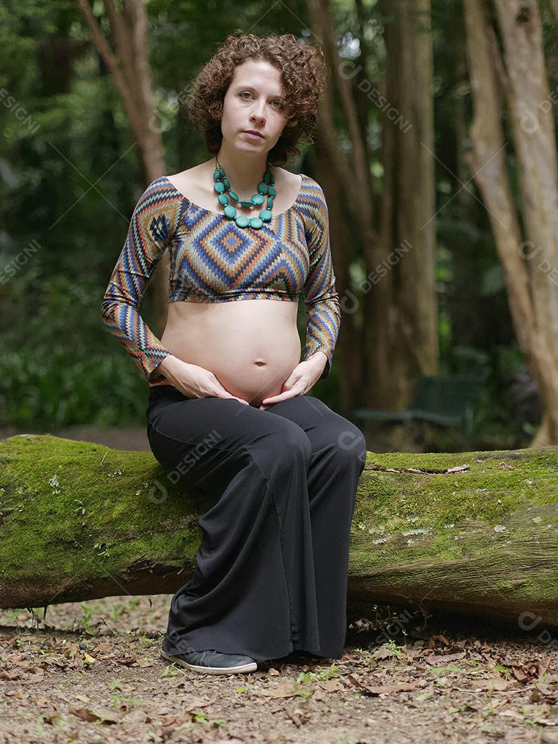 Mulher jovem moderna grávida tocando sua barriga ao ar livre.