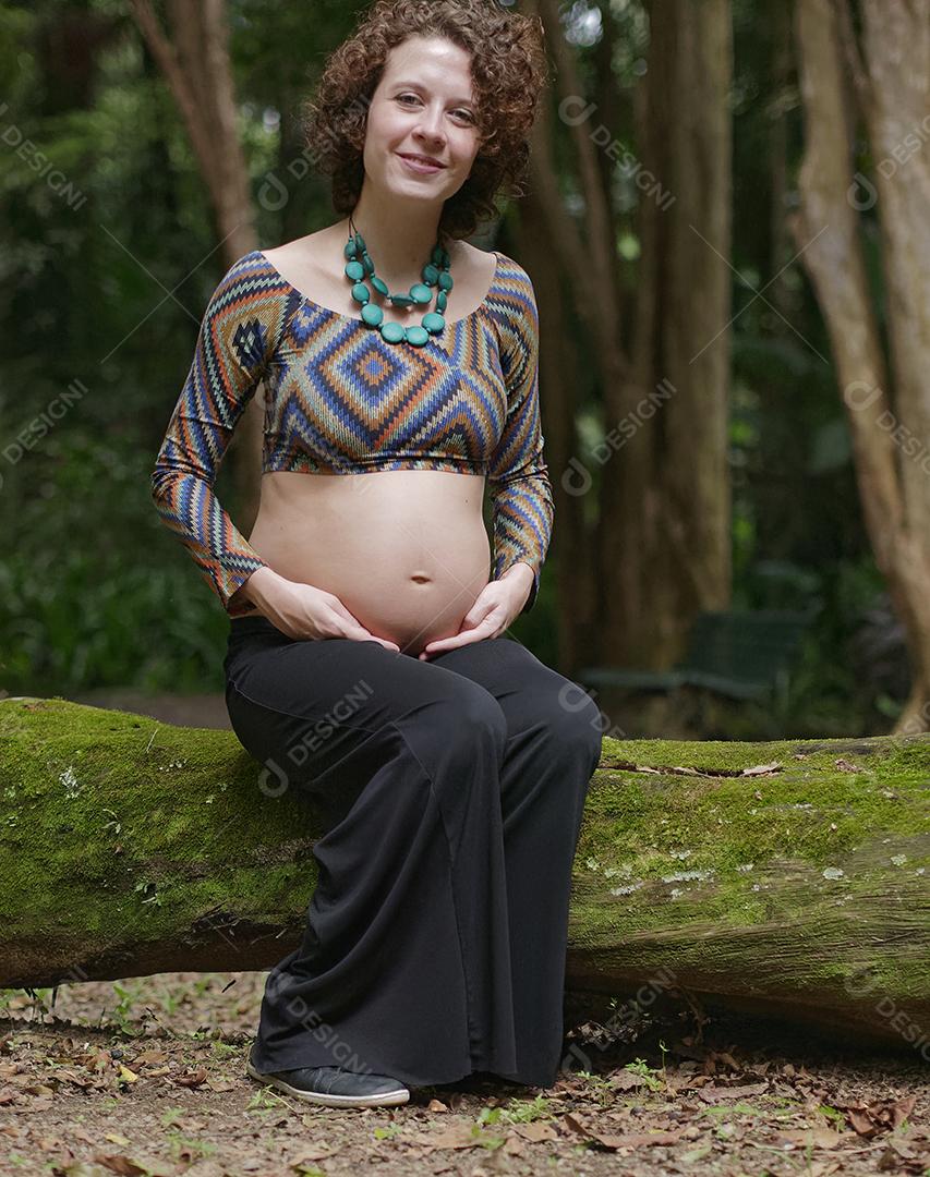 Mulher jovem moderna grávida tocando sua barriga ao ar livre.