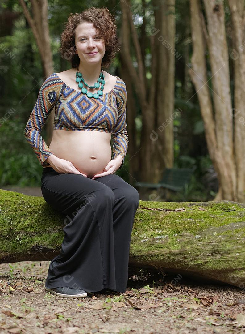 Mulher jovem moderna grávida tocando sua barriga ao ar livre.