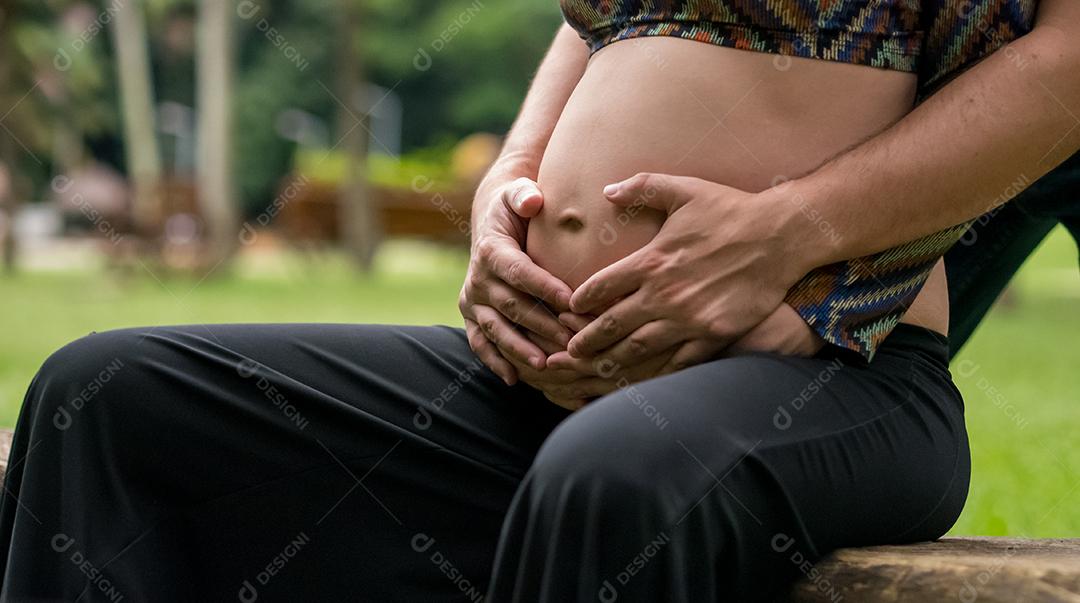 Mulher jovem moderna grávida tocando sua barriga ao ar livre.