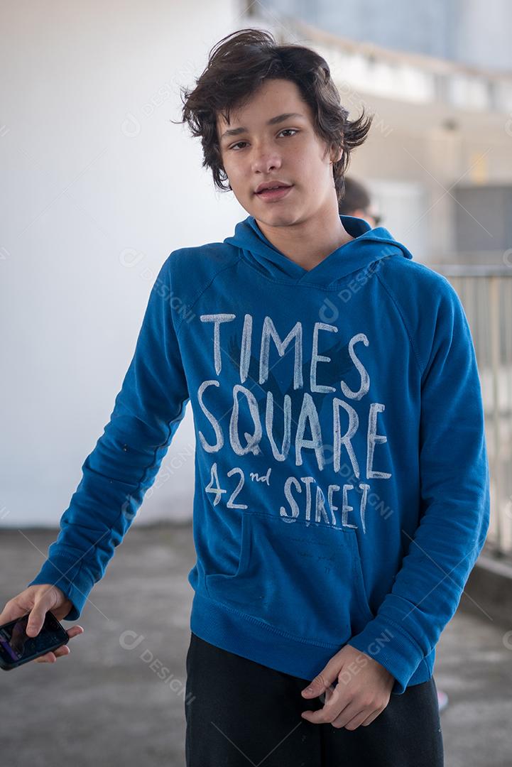 Menino segurando seu celular no telhado do prédio.