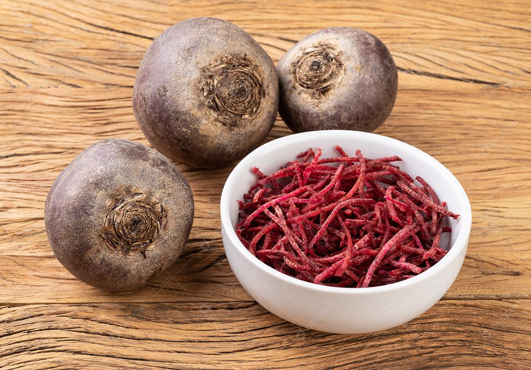 Beterraba e tiras de beterraba, estilo julienne em uma tigela sobre mesa de madeira.