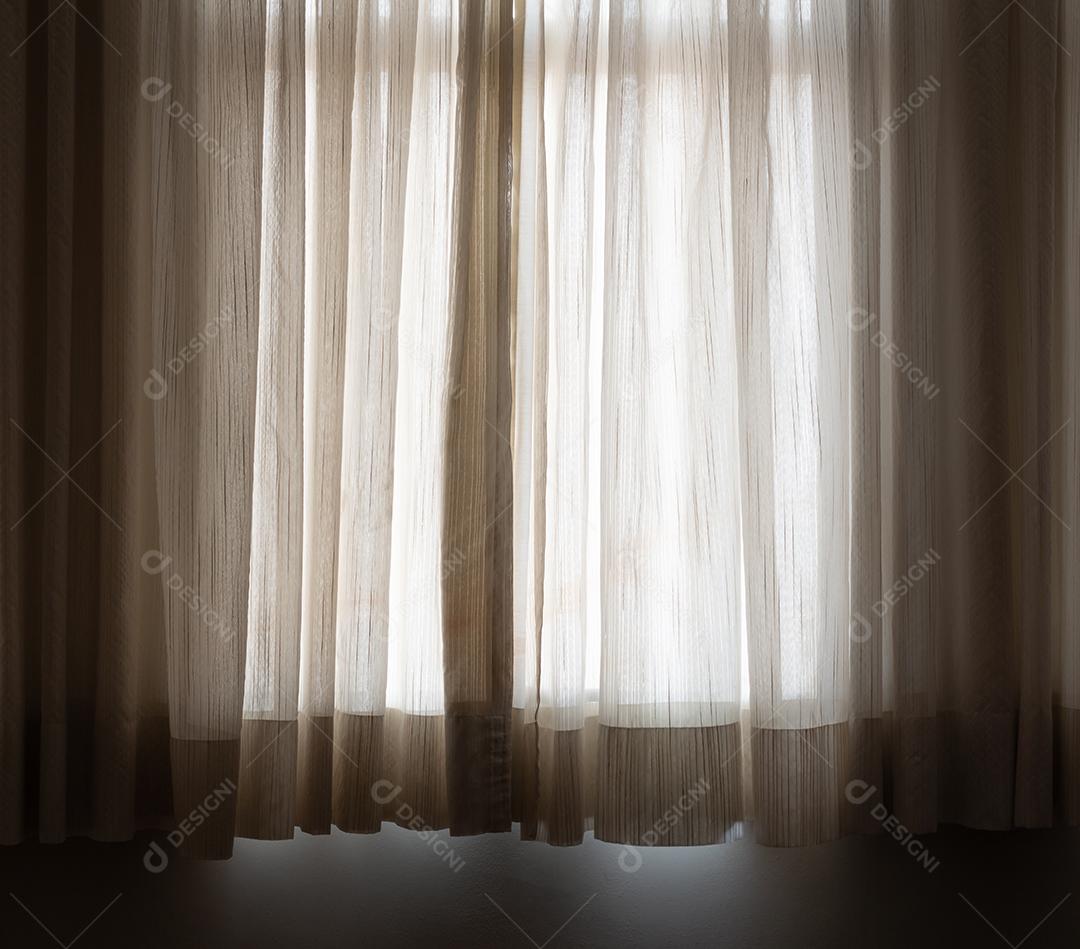 Cortina marrom clara em um quarto escuro em frente à janela.